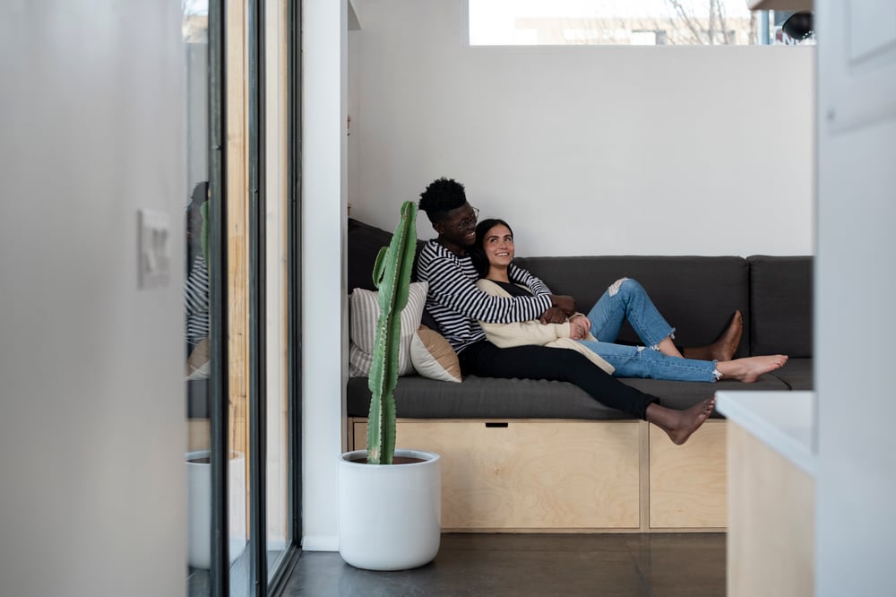 A couple sitting together on a couch with storage beneath them.
